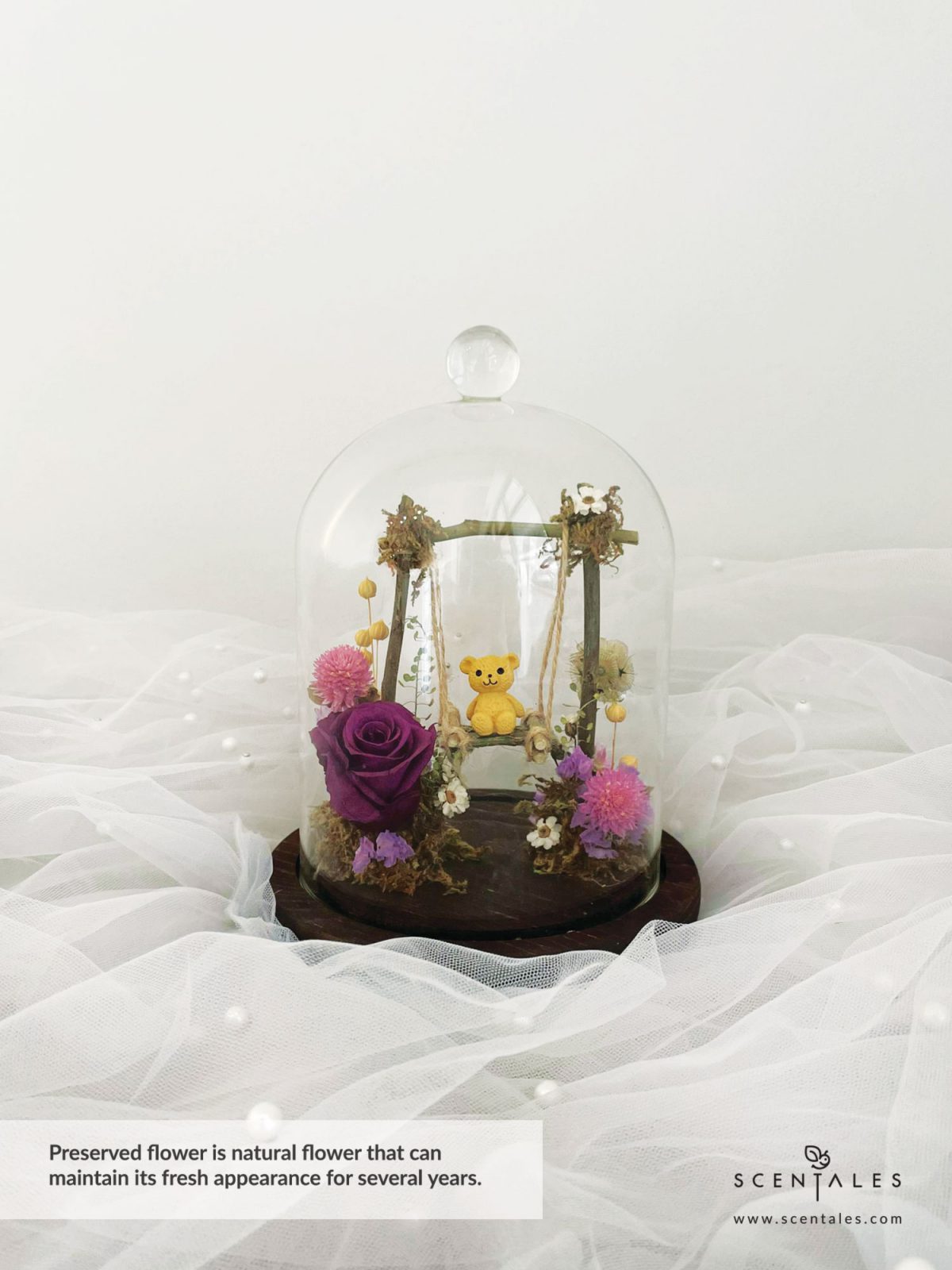 Dried and Preserved bell jar with Bear, swing, preserved dark purple rose, dried pink gomphrena, dried brown scabiosa stellata, ixodia, lilac statice, dried thlaspi, plenty of dried lino and moss