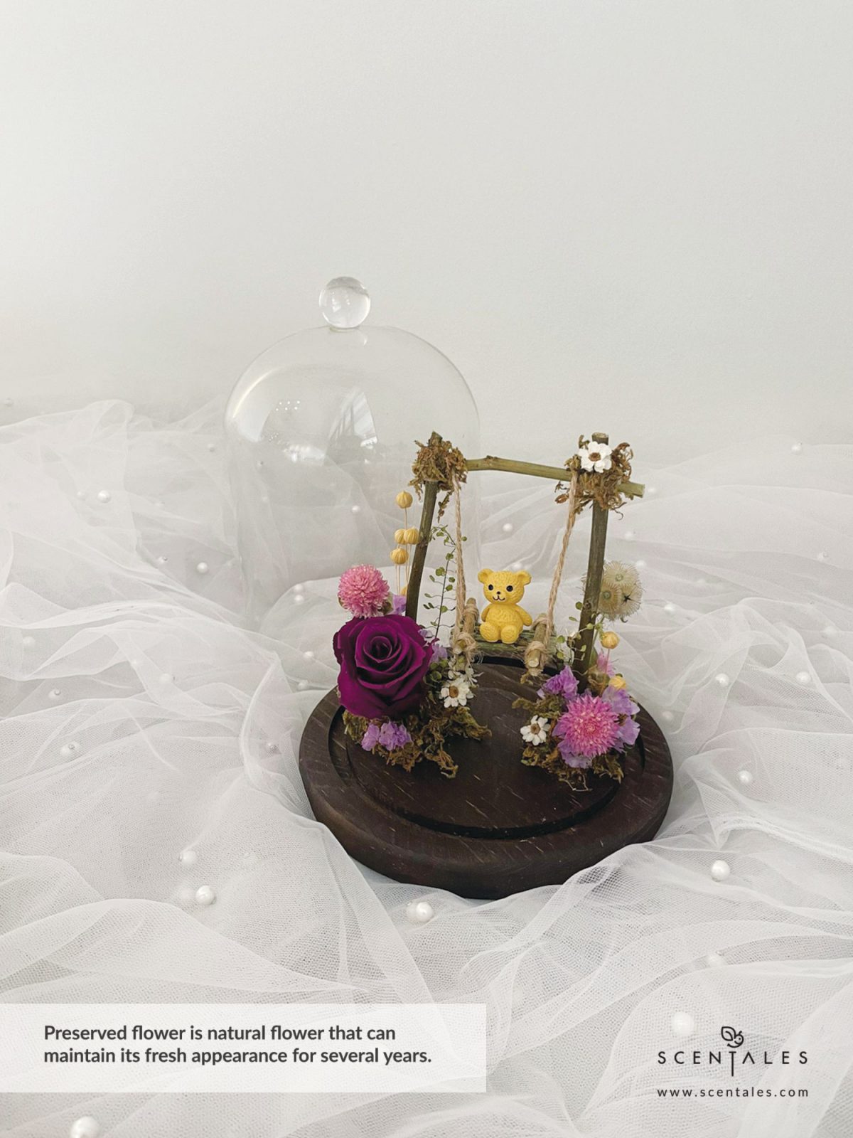 Dried and Preserved bell jar with Bear, swing, preserved dark purple rose, dried pink gomphrena, dried brown scabiosa stellata, ixodia, lilac statice, dried thlaspi, plenty of dried lino and moss