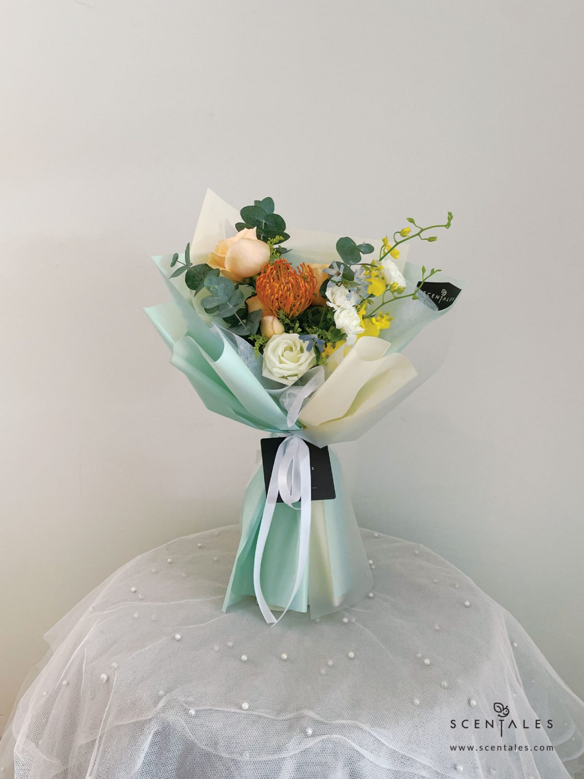 Fresh flower bouquet with Orange leucospermum, champagne rose, champagne spray rose, yellow dancing lady, light blue mini delphinium, white eustoma bud, white spray carnation, yellow peacock and plenty of eucalyptus cinerea