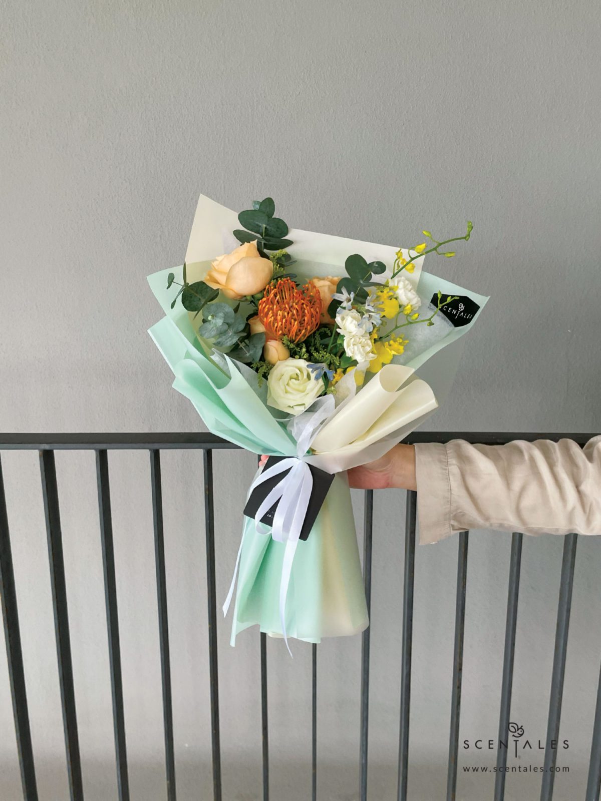 Fresh flower bouquet with Orange leucospermum, champagne rose, champagne spray rose, yellow dancing lady, light blue mini delphinium, white eustoma bud, white spray carnation, yellow peacock and plenty of eucalyptus cinerea