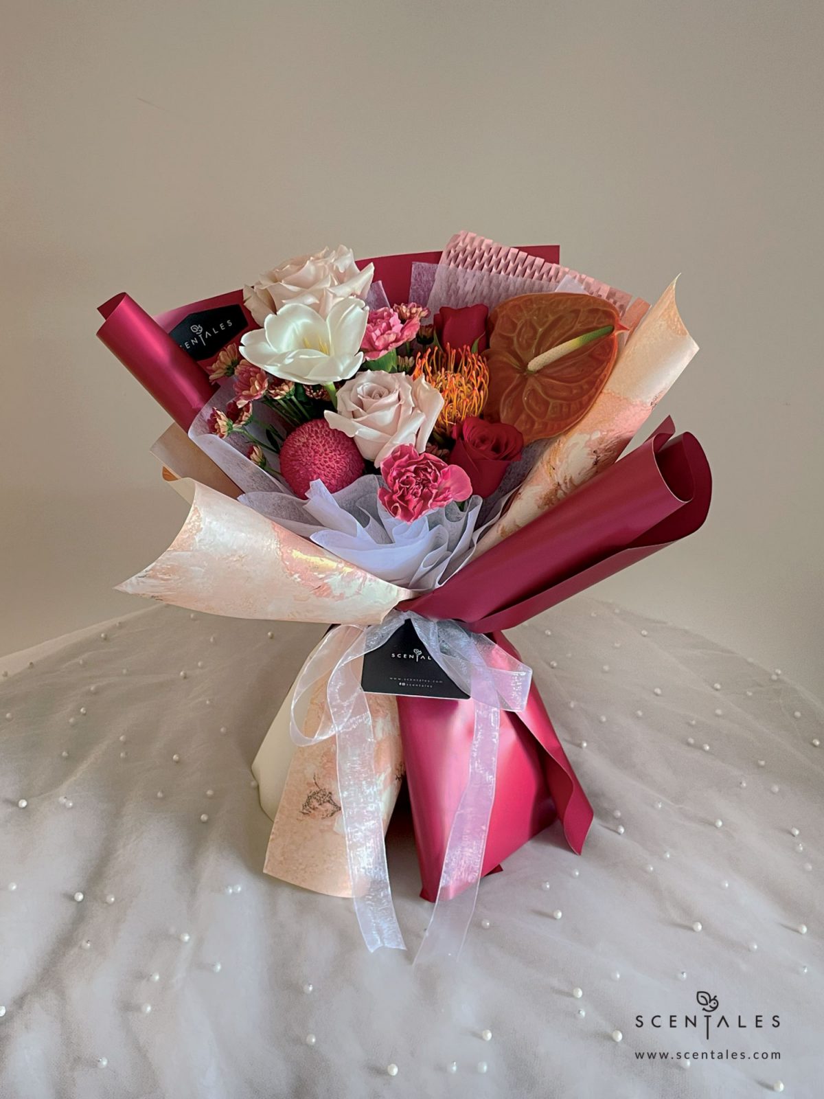 fresh flower with Quicksand rose, red rose, red leucospermum, white tulip, love of cuba carnation, maroon ping pong, anthurium and rossi smokey calimero pom pom