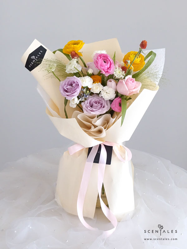 New Beginnings Flower Bouquet Fresh flower bouquet with Pink tulip, lilac rose, pink rose, pink ranunculus, yellow ranunculus, blue oxypetalum, white spray carnation, white trachymene, orange gomphrena and panicum