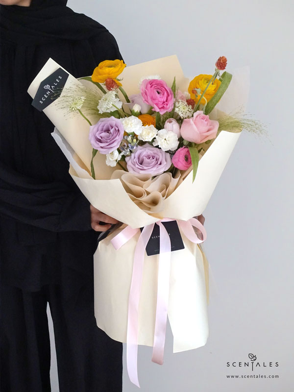 New Beginnings Flower Bouquet Fresh flower bouquet with Pink tulip, lilac rose, pink rose, pink ranunculus, yellow ranunculus, blue oxypetalum, white spray carnation, white trachymene, orange gomphrena and panicum