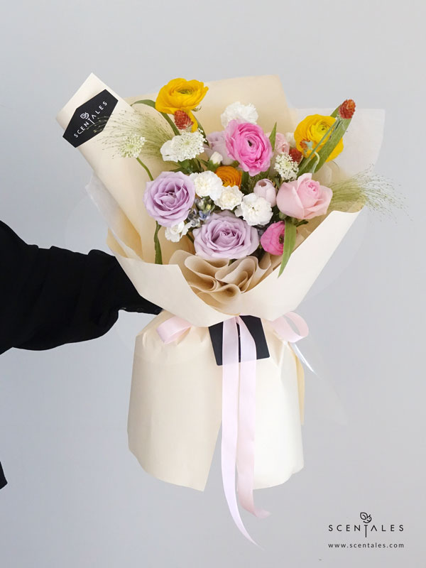 New Beginnings Flower Bouquet Fresh flower bouquet with Pink tulip, lilac rose, pink rose, pink ranunculus, yellow ranunculus, blue oxypetalum, white spray carnation, white trachymene, orange gomphrena and panicum